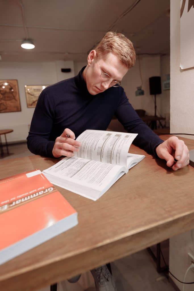 Man flipping through a grammr book with another grammer related book by his side